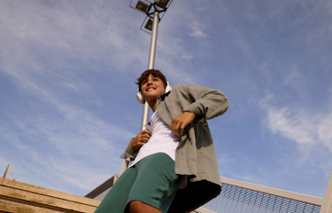 Actor portrayal of an adult male smiling wearing white headphones