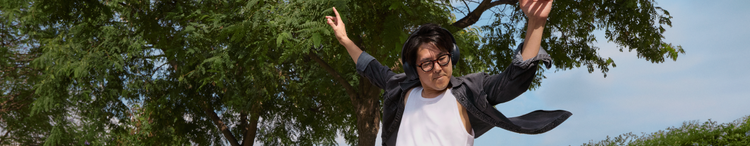 Actor portrayl of an adult male dancing with his arms raised wearing black headphones