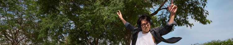 Actor portrayl of an adult male dancing with his arms raised wearing black headphones